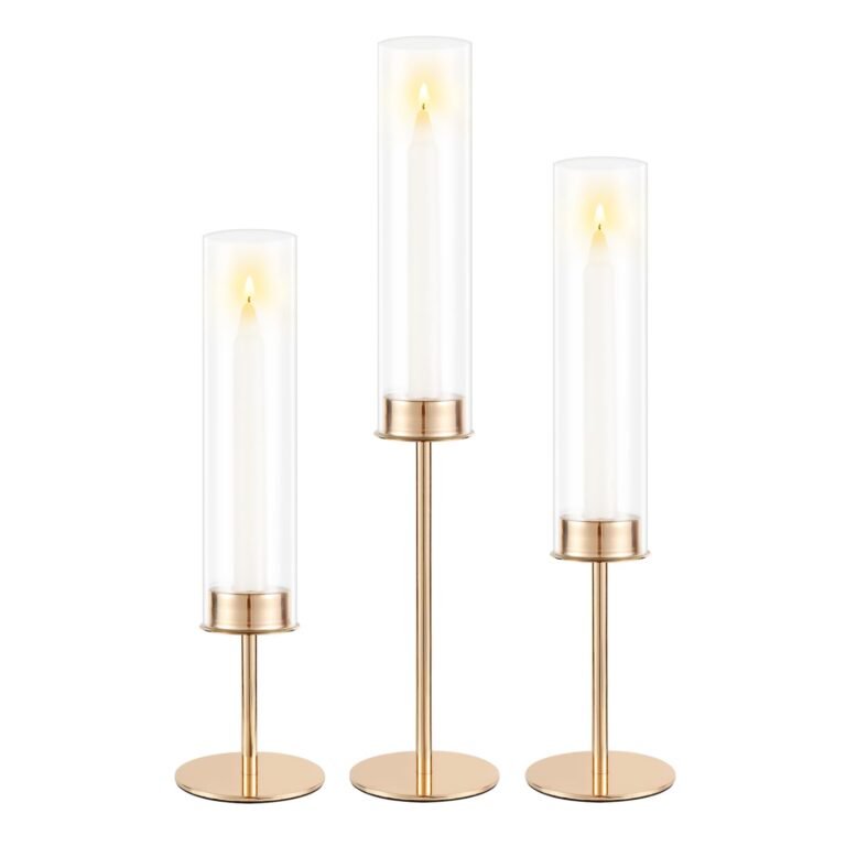 Three gold candle holders with lit candles inside clear glass cylinders