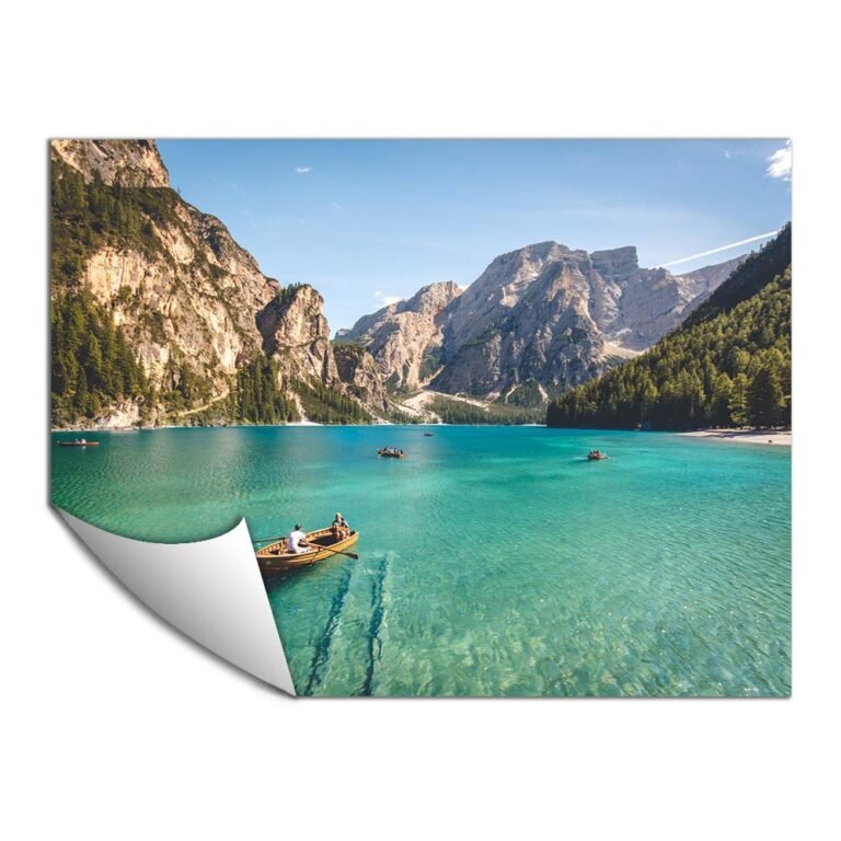 Turquoise lake with boats, surrounded by mountains and trees under a blue sky