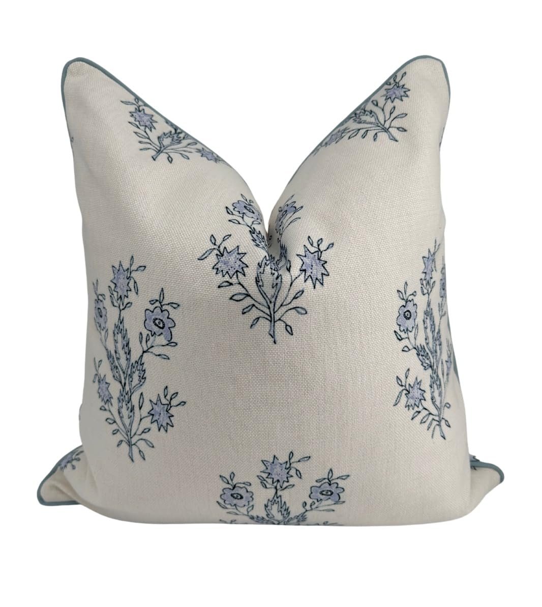 Cream-colored pillow with blue floral pattern and teal trim