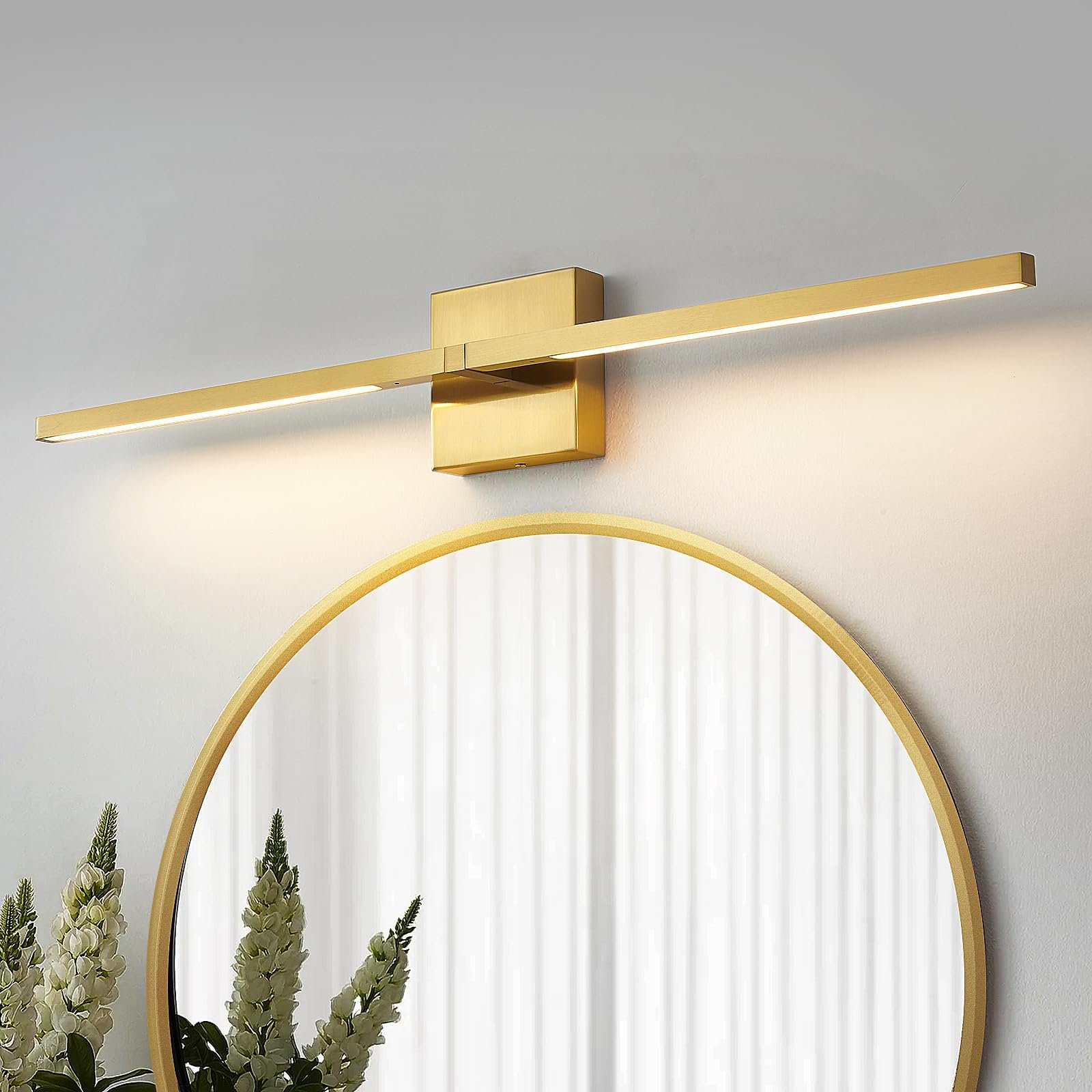 Gold wall-mounted light fixture above a round mirror with flowers