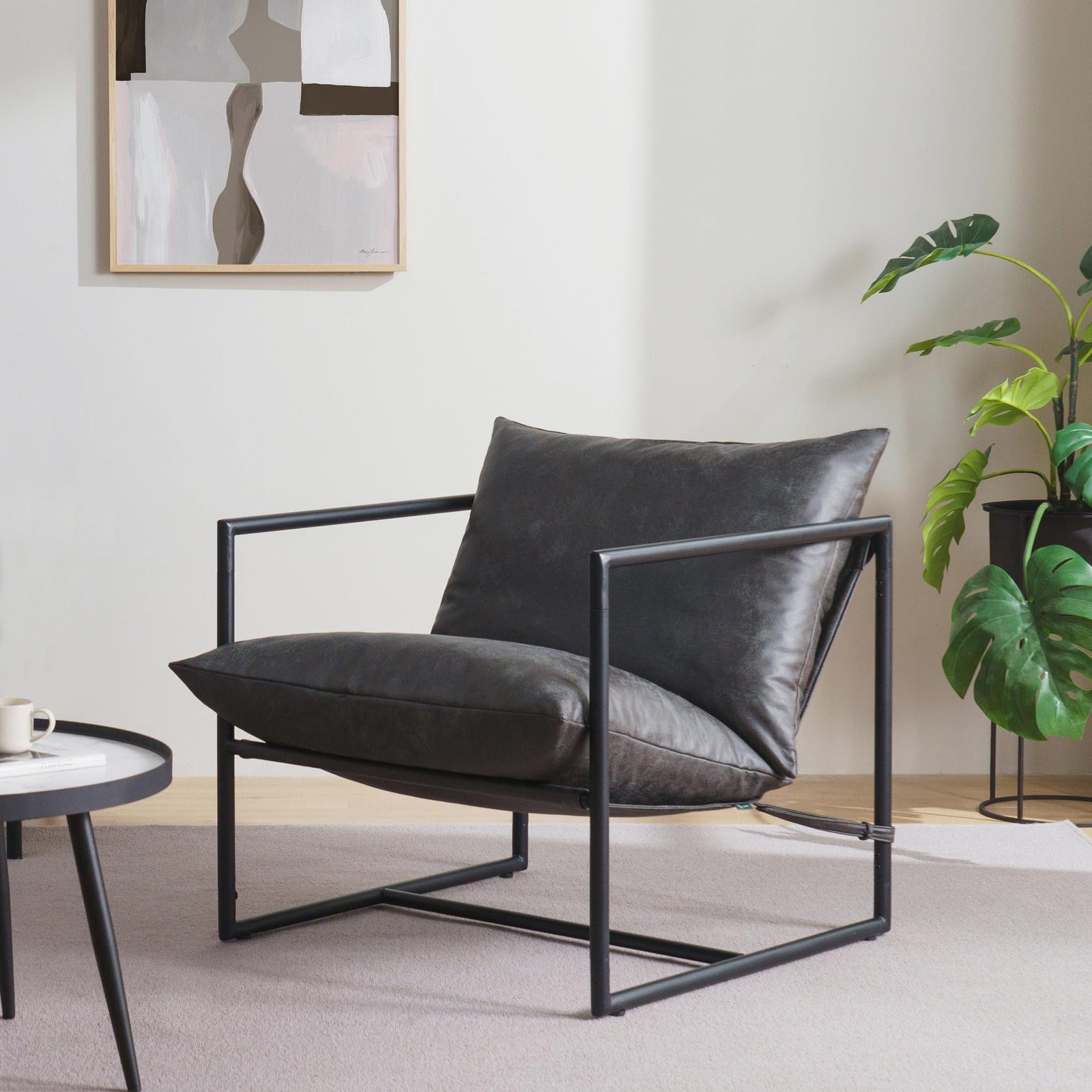 Modern black leather armchair with a metal frame, next to a plant