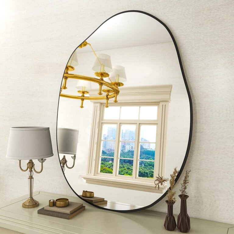 Oval mirror reflecting a window, chandelier, and a lamp on a dresser