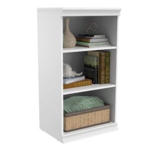 White bookshelf with books, vase, seashell, and a basket with a blanket