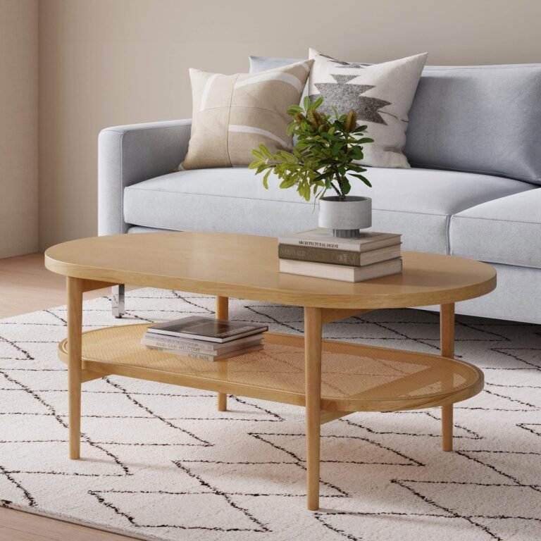 Oval wooden coffee table with books, plant, and woven shelf, in front of sofa