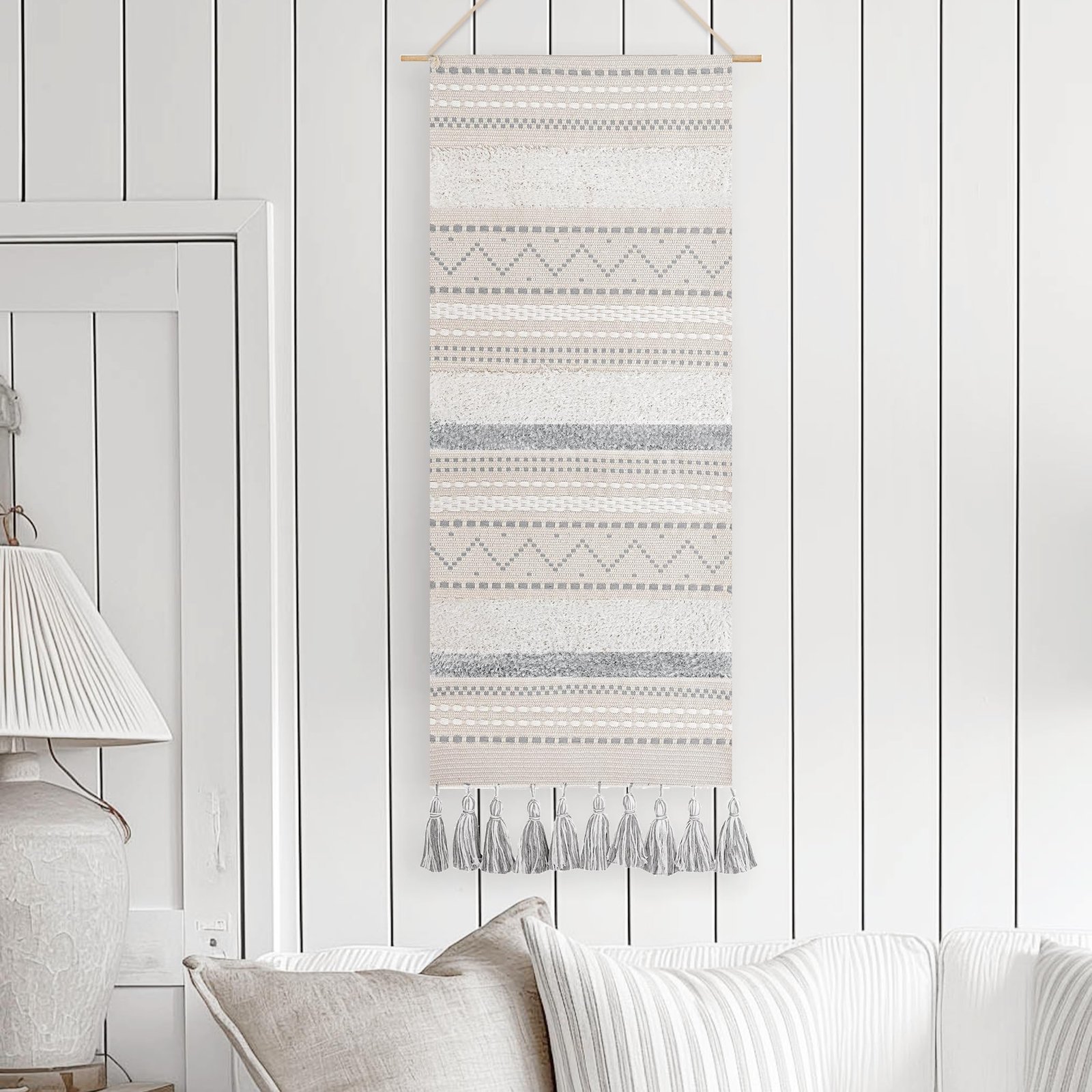 Textile wall hanging with tassels, hanging on a white paneled wall