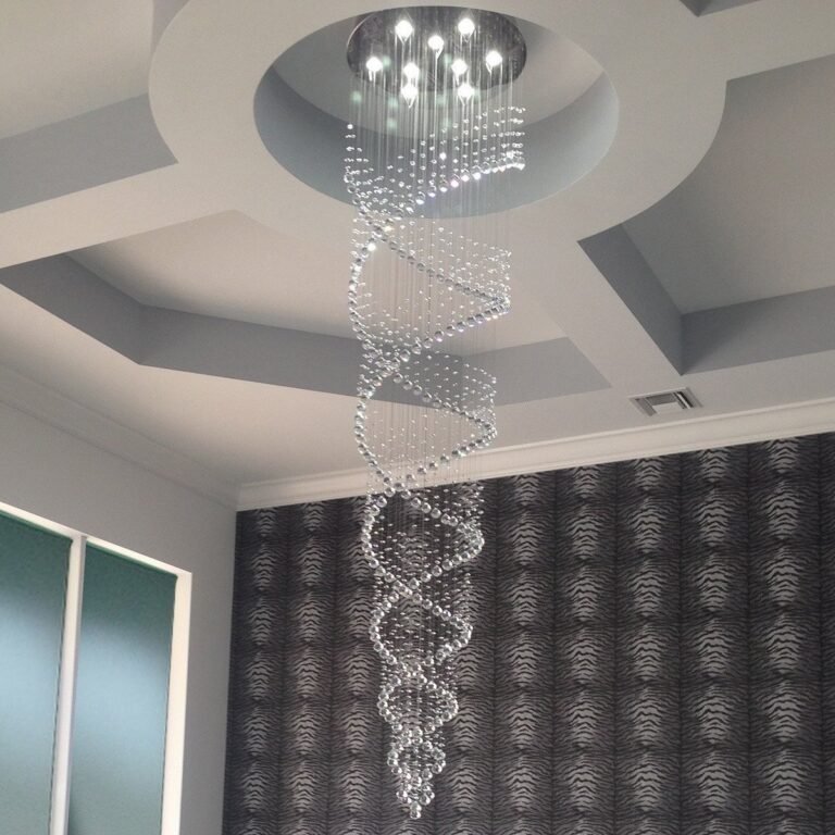 Spiral crystal chandelier hanging from a recessed ceiling, patterned wallpaper