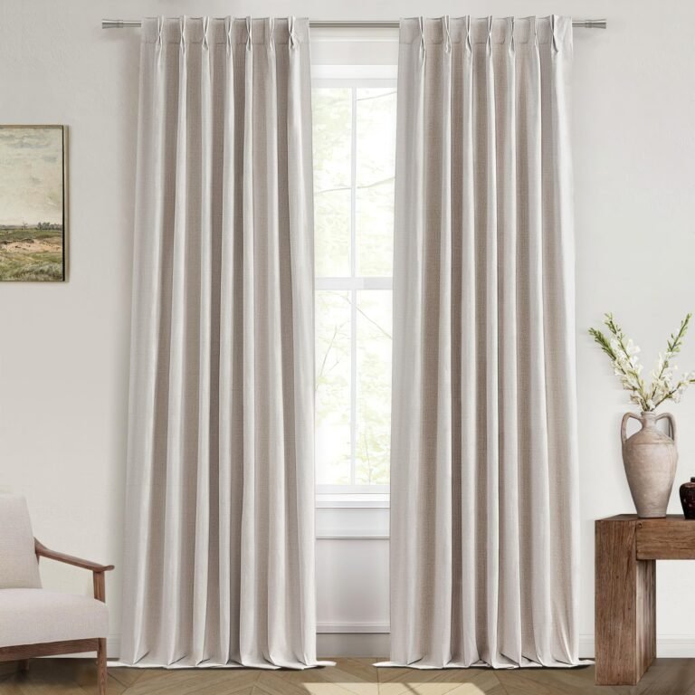 Beige curtains frame a window, with a painting and side table with vase