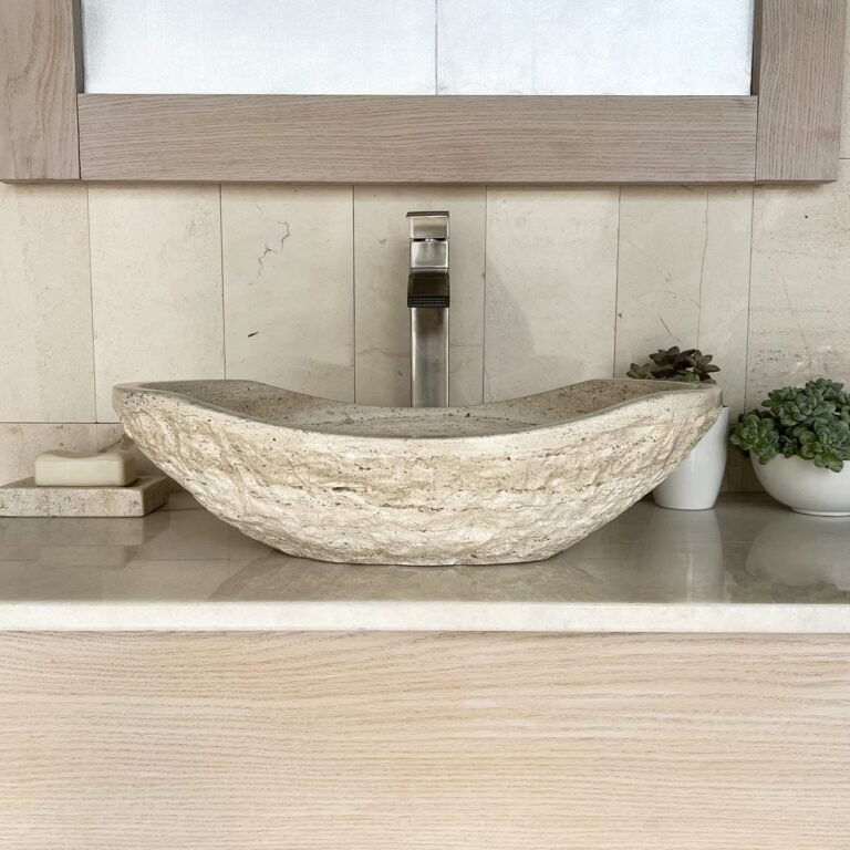 Bathroom sink with stone basin, faucet, mirror, and small plants